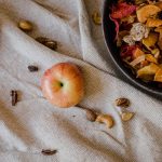 Warm autumnal flat lay with apples, dried fruits, and nuts on textured fabric.