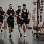 Group of men running in an indoor fitness competition, showcasing athleticism and determination.